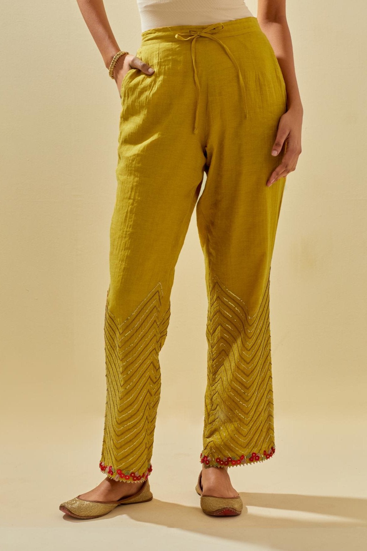 Yellow tissue chanderi straight pants with hand cut silk flower embroidery at hem, highlighted with gold sequins and beads.