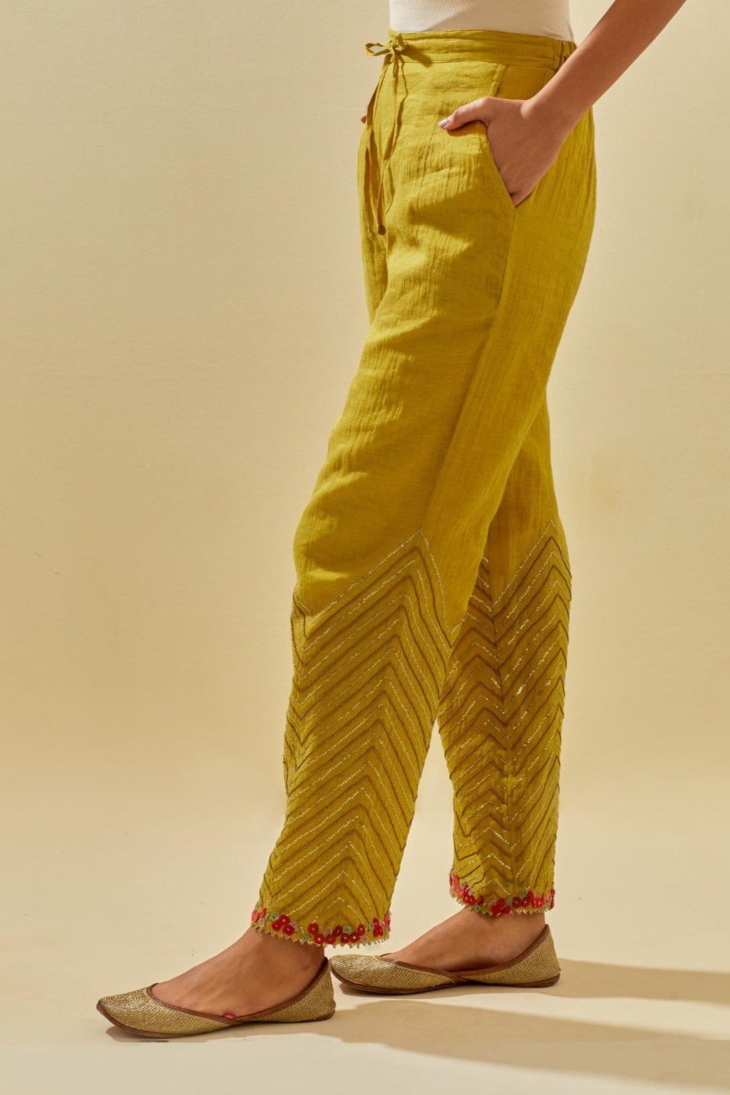 Yellow tissue chanderi straight pants with hand cut silk flower embroidery at hem, highlighted with gold sequins and beads.
