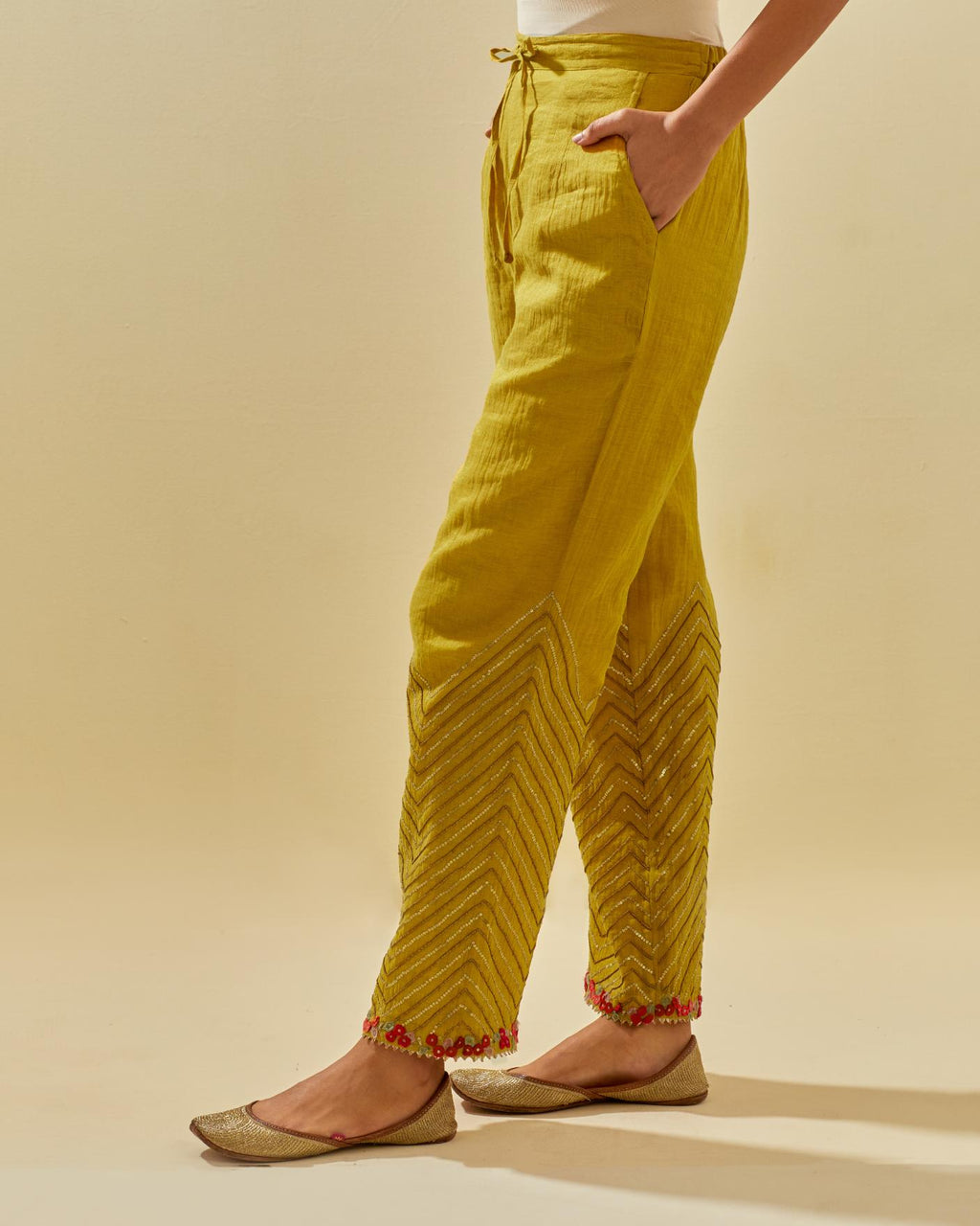 Yellow tissue chanderi straight pants with hand cut silk flower embroidery at hem, highlighted with gold sequins and beads.