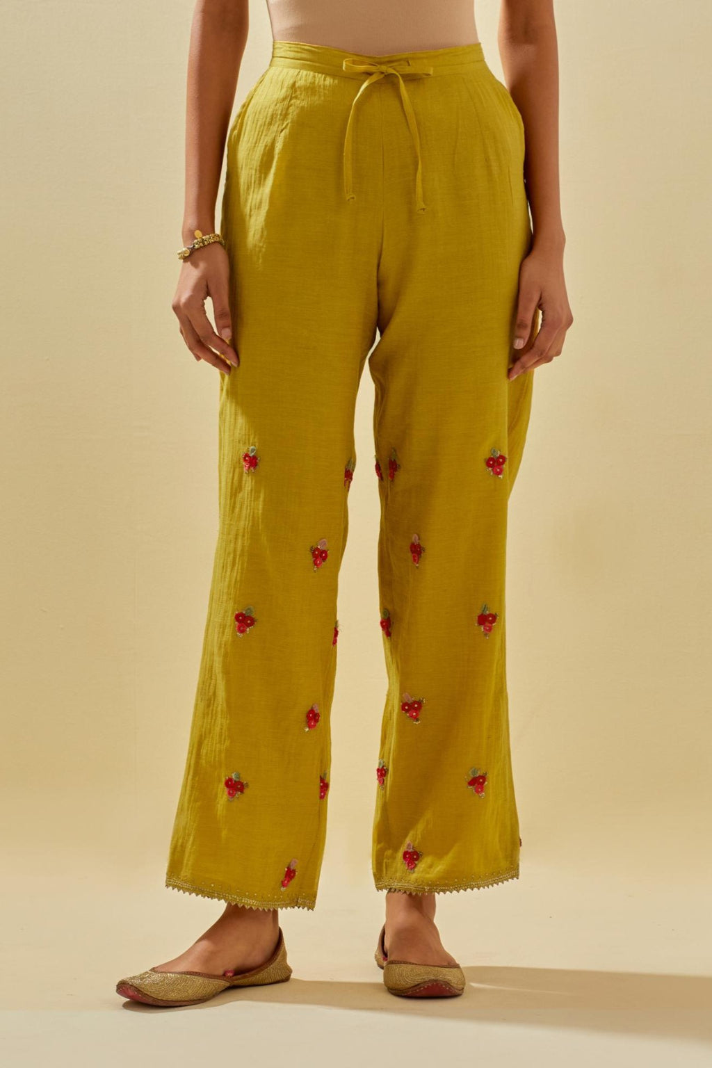 Yellow tissue chanderi straight pants with hand cut silk flower embroidered booti, highlighted with gold sequins.