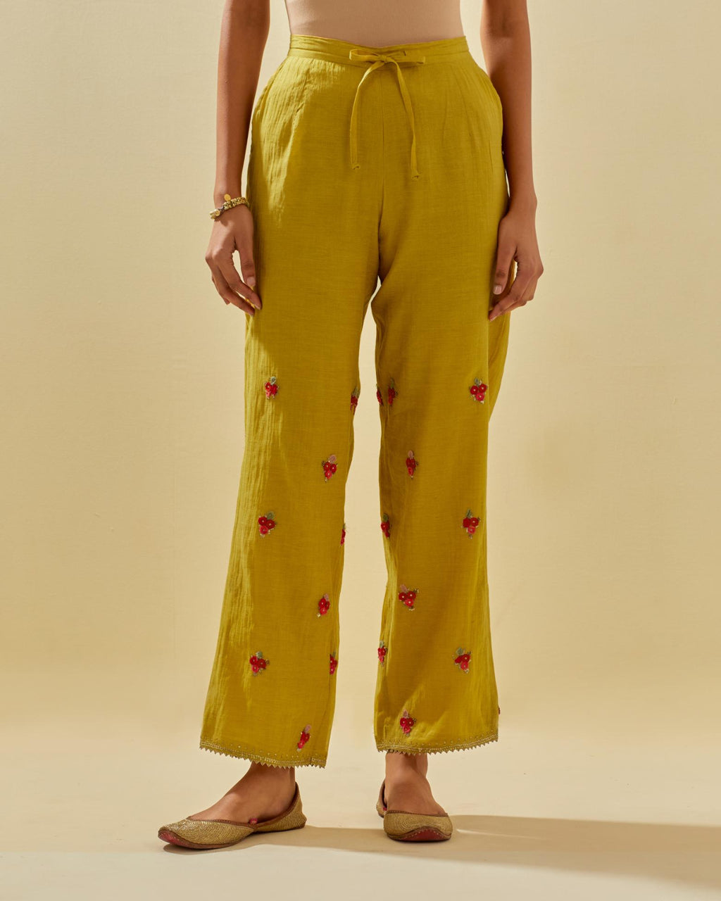 Yellow tissue chanderi straight pants with hand cut silk flower embroidered booti, highlighted with gold sequins.