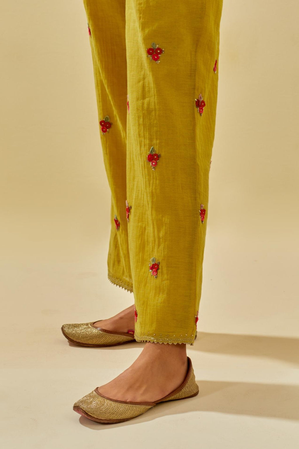 Yellow tissue chanderi straight pants with hand cut silk flower embroidered booti, highlighted with gold sequins.