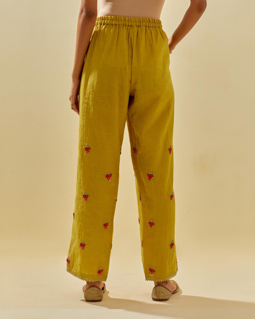 Yellow tissue chanderi straight pants with hand cut silk flower embroidered booti, highlighted with gold sequins.