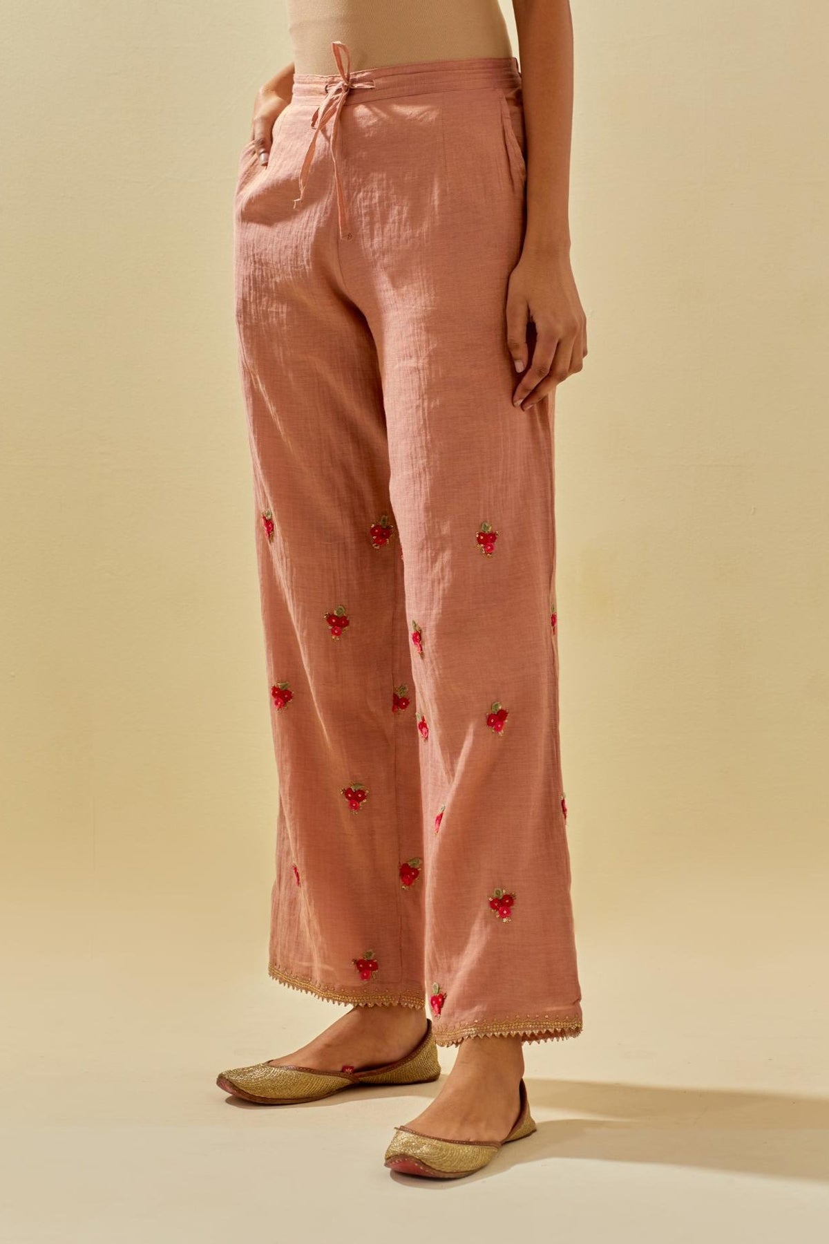 Pink tissue chanderi straight pants with hand cut silk flower embroidered booti, highlighted with gold sequins.