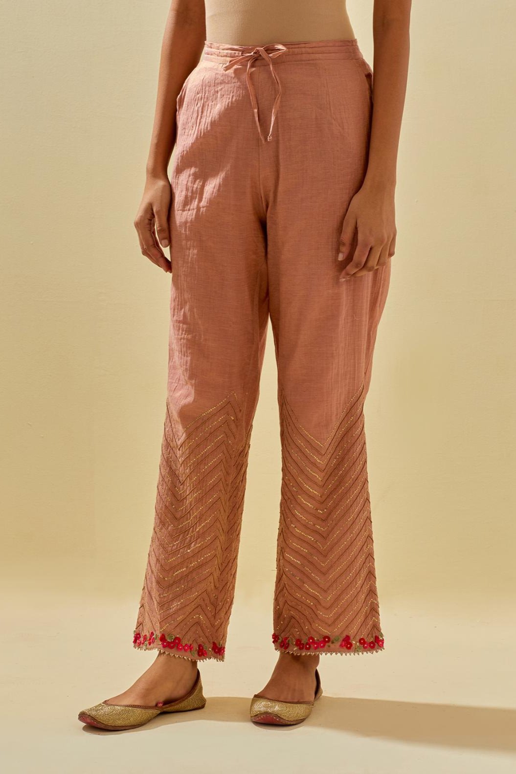 Pink tissue chanderi straight pants with hand cut silk flower embroidery at hem, highlighted with gold sequins and beads.