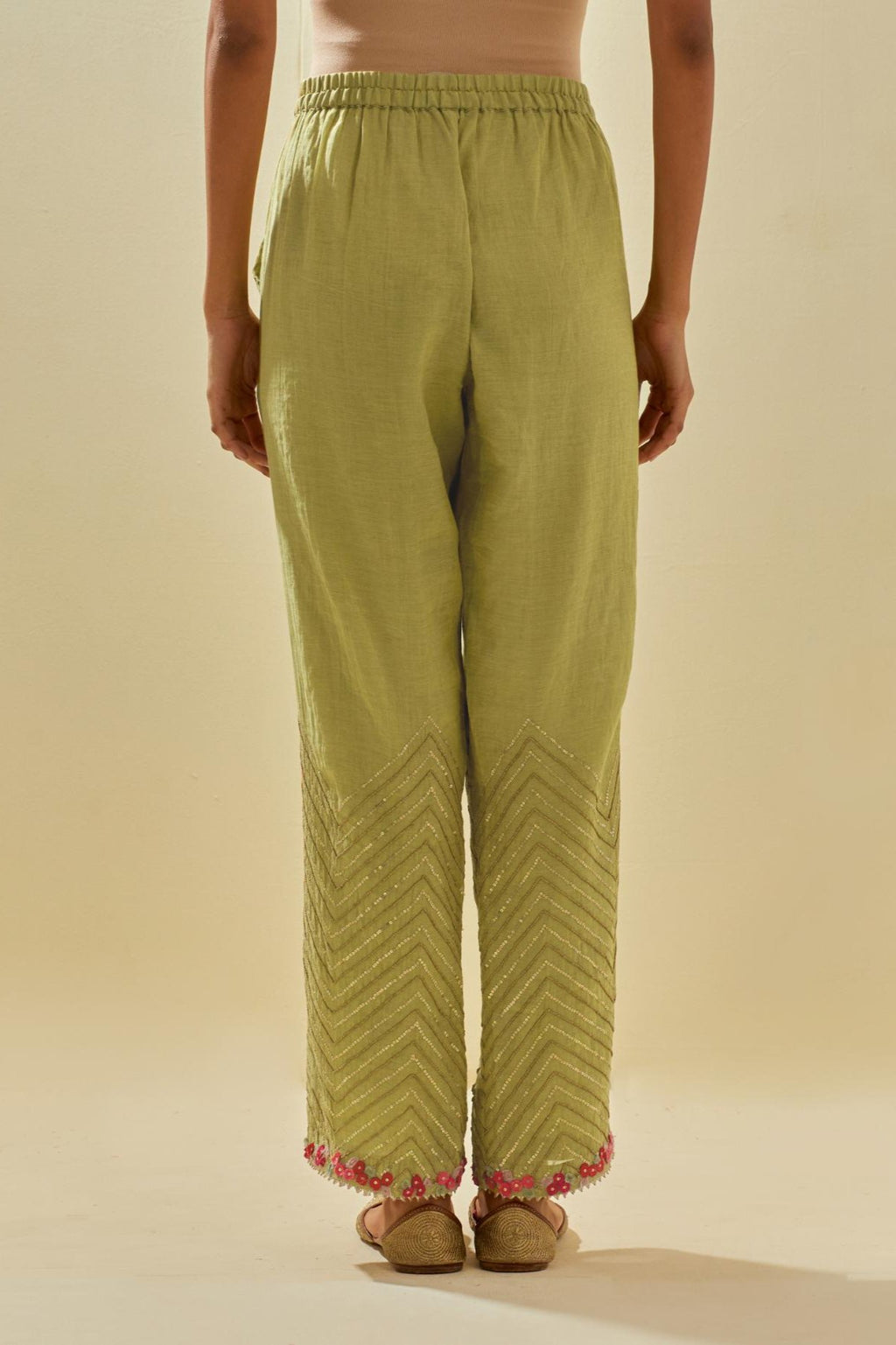 Green tissue chanderi straight pants with hand cut silk flower embroidery at hem, highlighted with gold sequins and beads.