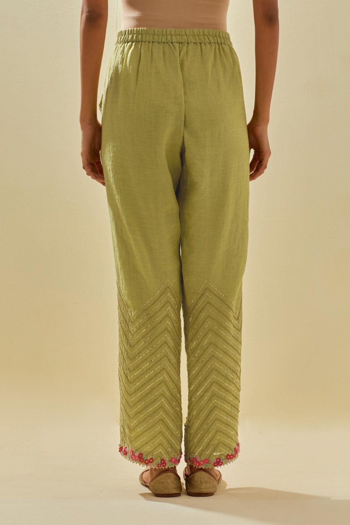 Green tissue chanderi straight pants with hand cut silk flower embroidery at hem, highlighted with gold sequins and beads.