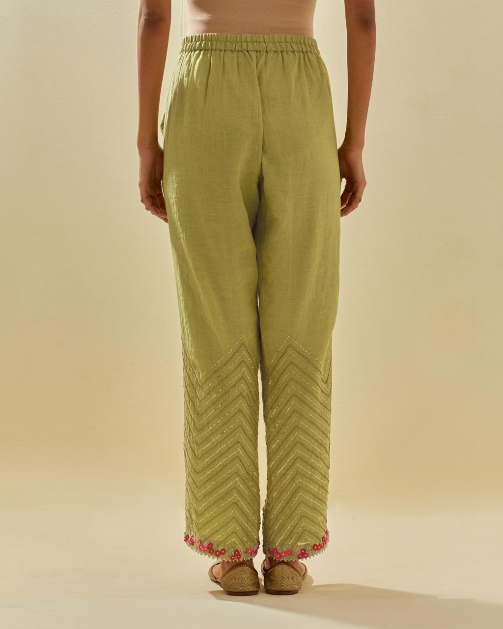 Green tissue chanderi straight pants with hand cut silk flower embroidery at hem, highlighted with gold sequins and beads.