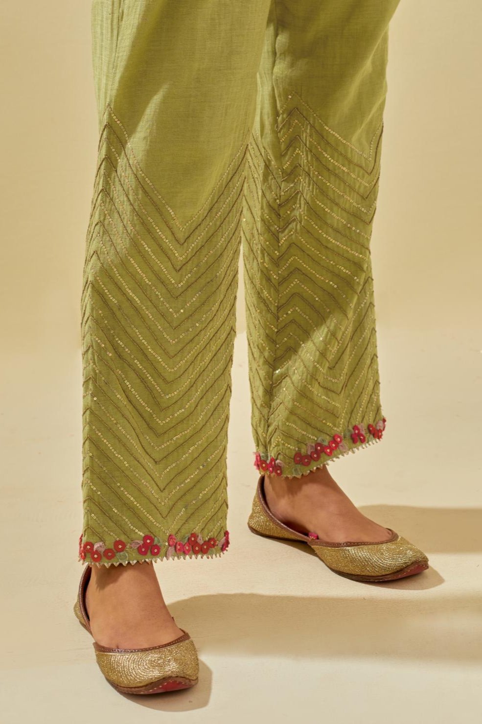 Green tissue chanderi straight pants with hand cut silk flower embroidery at hem, highlighted with gold sequins and beads.