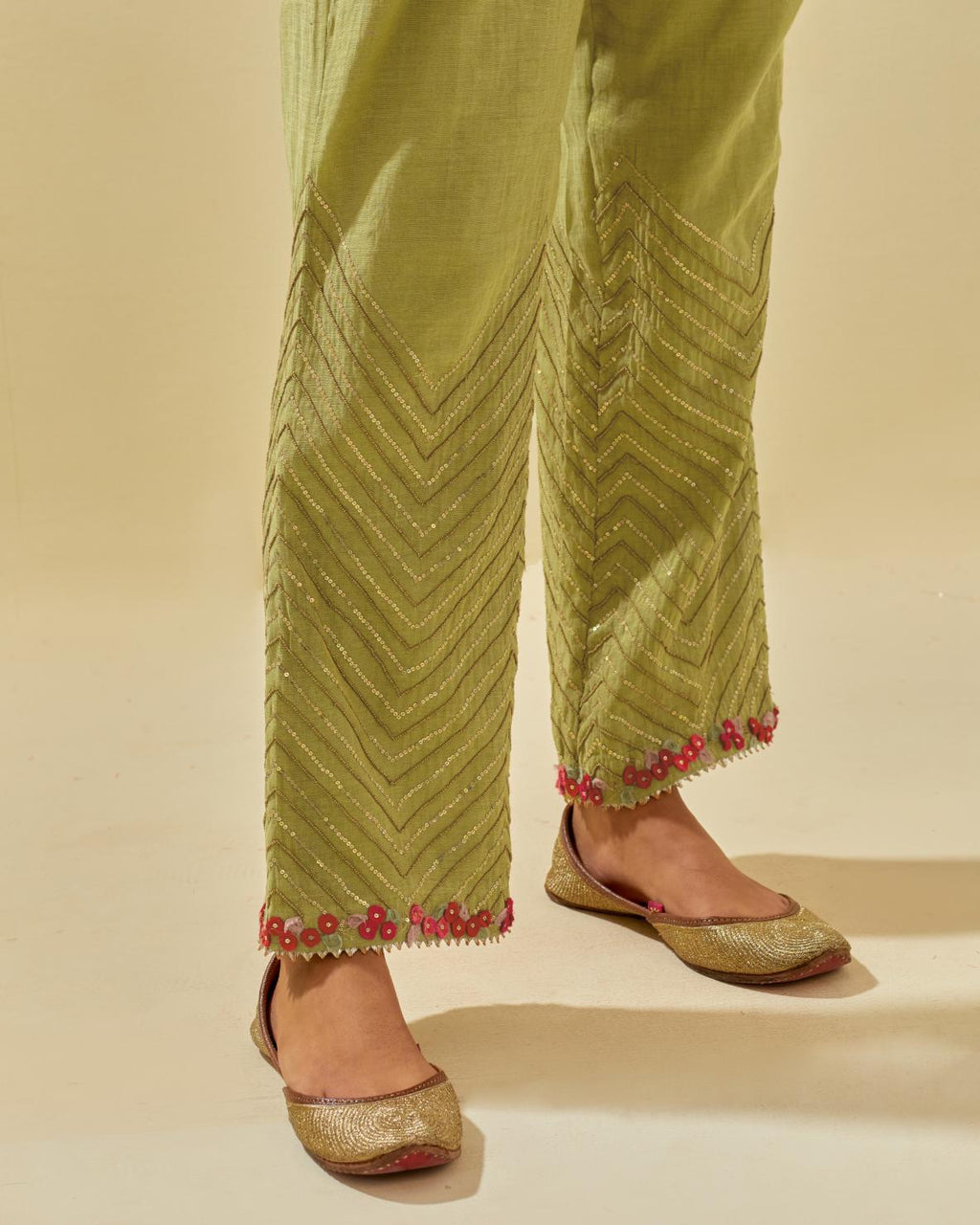 Green tissue chanderi straight pants with hand cut silk flower embroidery at hem, highlighted with gold sequins and beads.