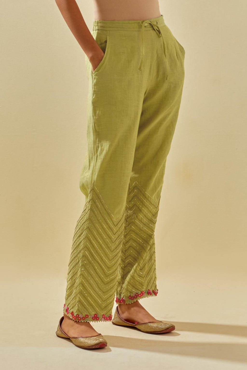 Green tissue chanderi straight pants with hand cut silk flower embroidery at hem, highlighted with gold sequins and beads.