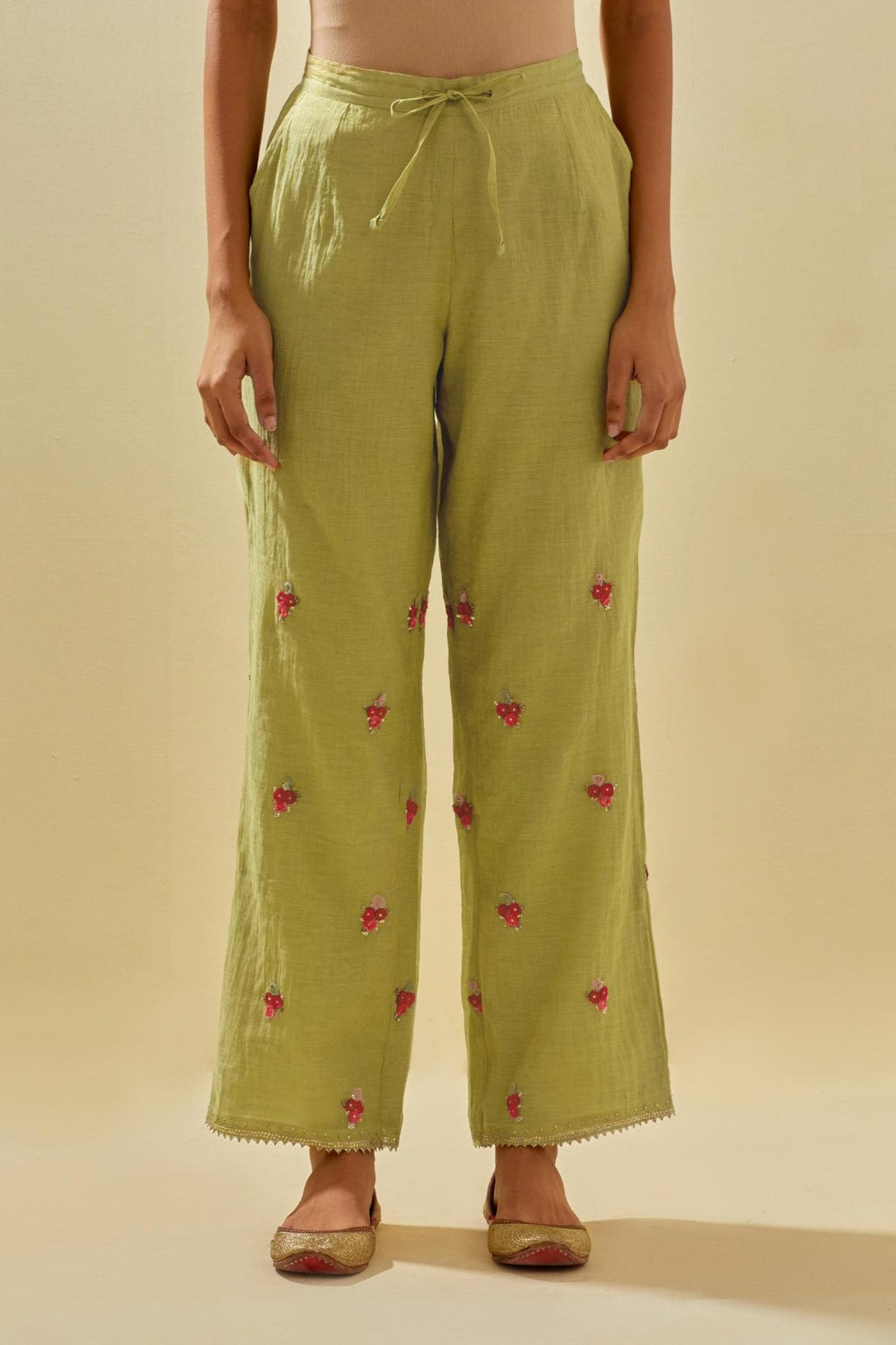 Green tissue chanderi straight pants with hand cut silk flower embroidered booti, highlighted with gold sequins.