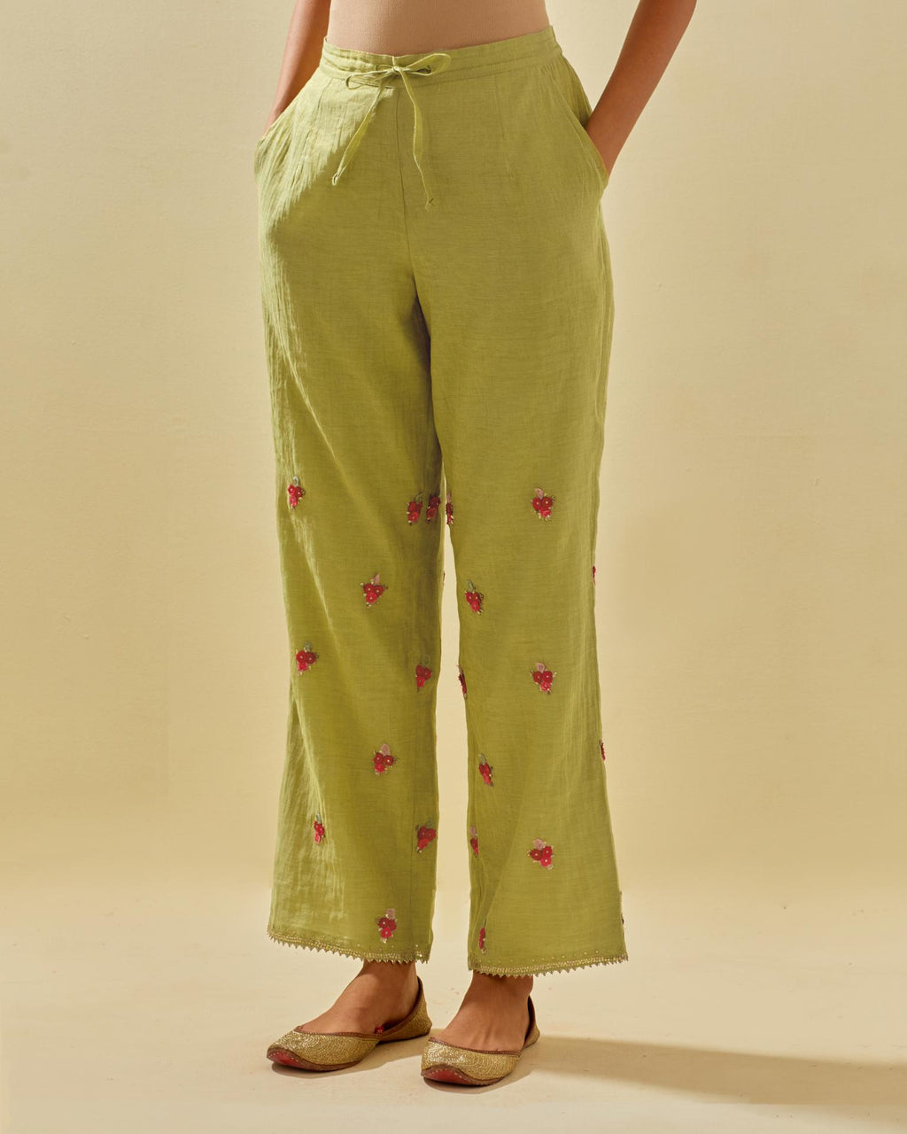 Green tissue chanderi straight pants with hand cut silk flower embroidered booti, highlighted with gold sequins.