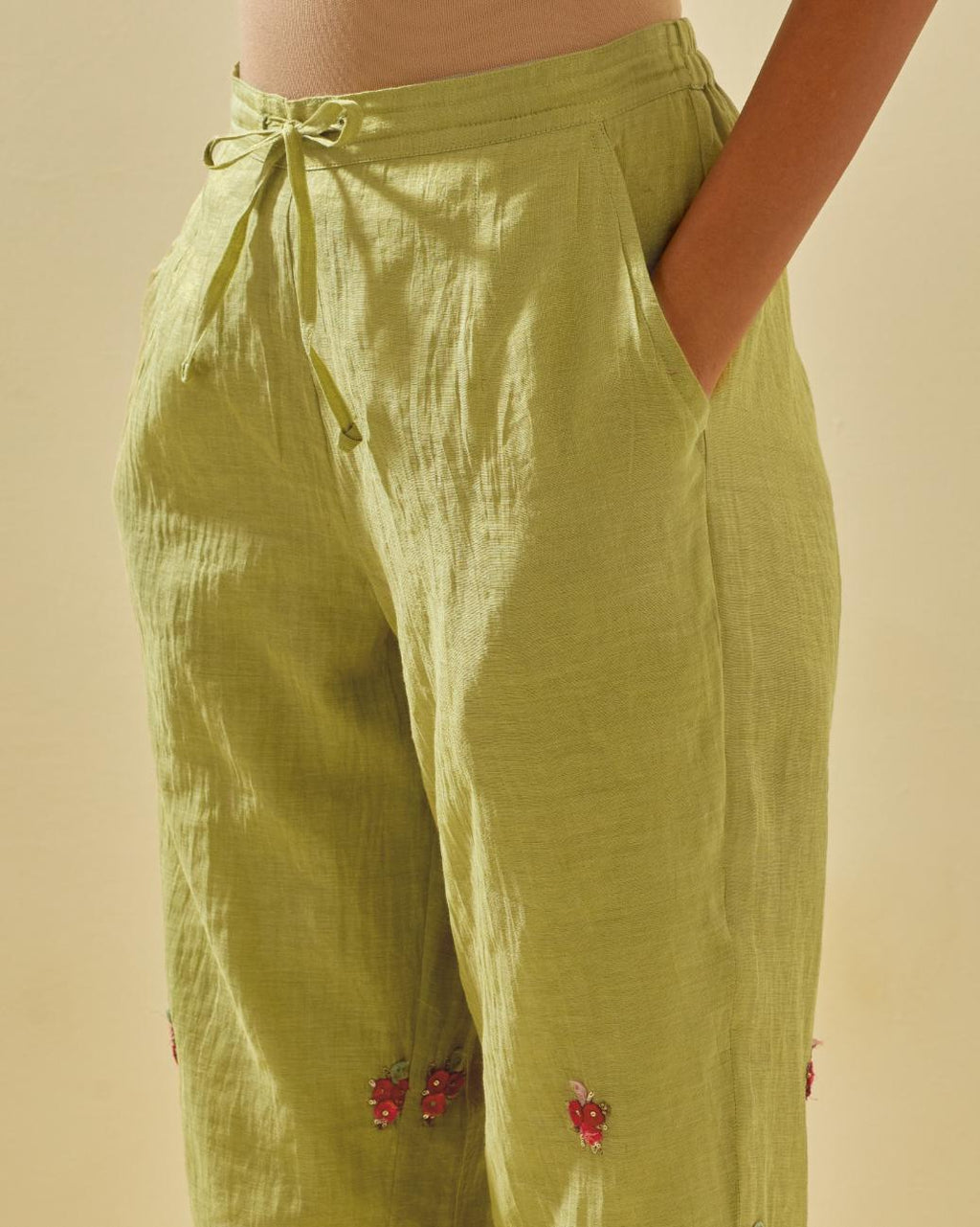 Green tissue chanderi straight pants with hand cut silk flower embroidered booti, highlighted with gold sequins.