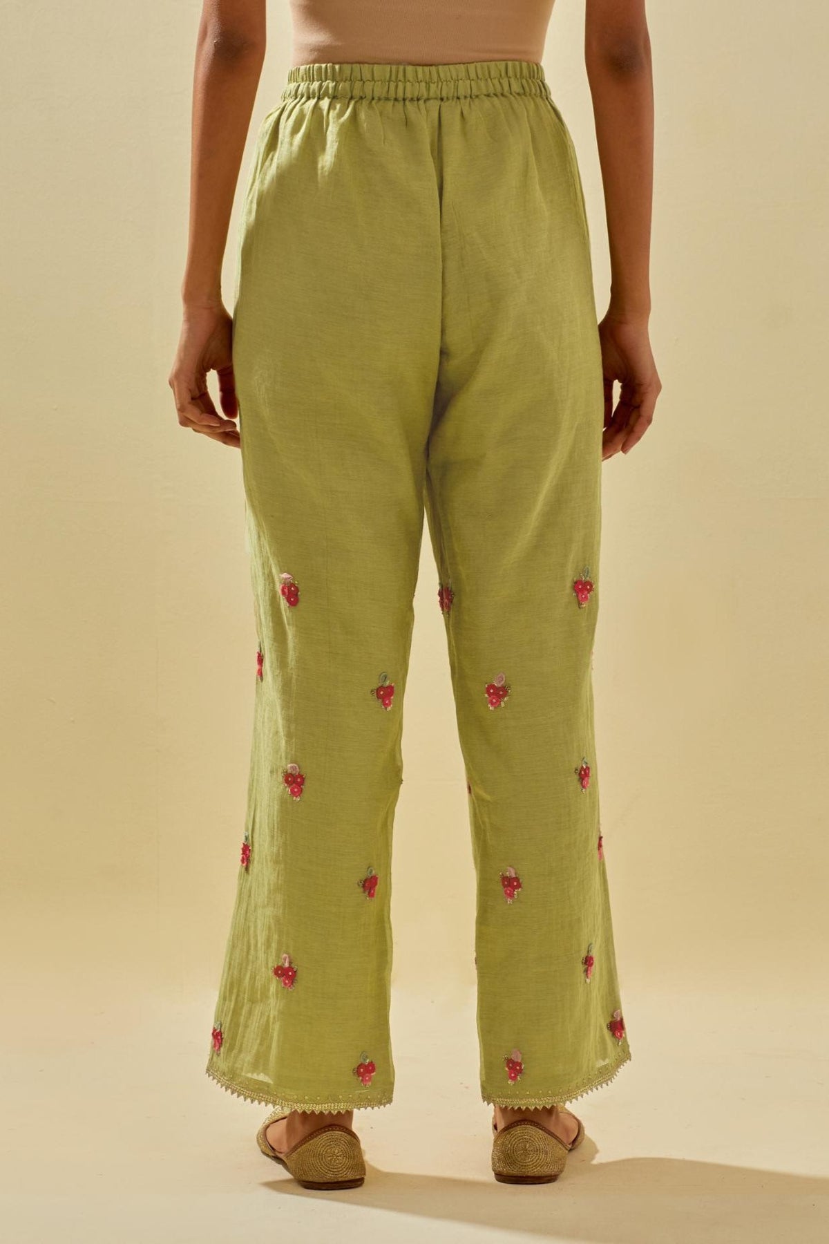 Green tissue chanderi straight pants with hand cut silk flower embroidered booti, highlighted with gold sequins.