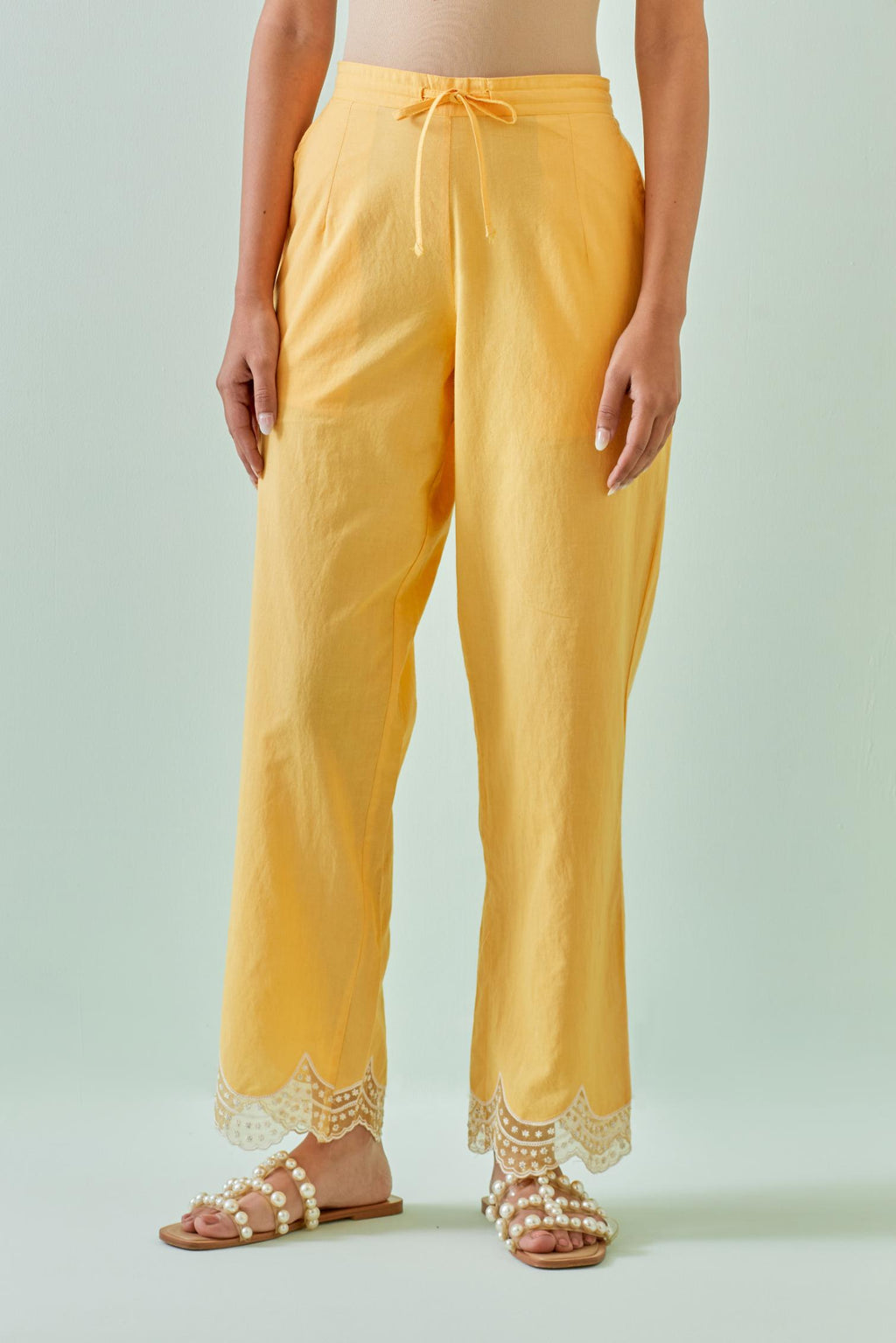 Yellow straight pants with scalloped embroidery at bottom hem.
