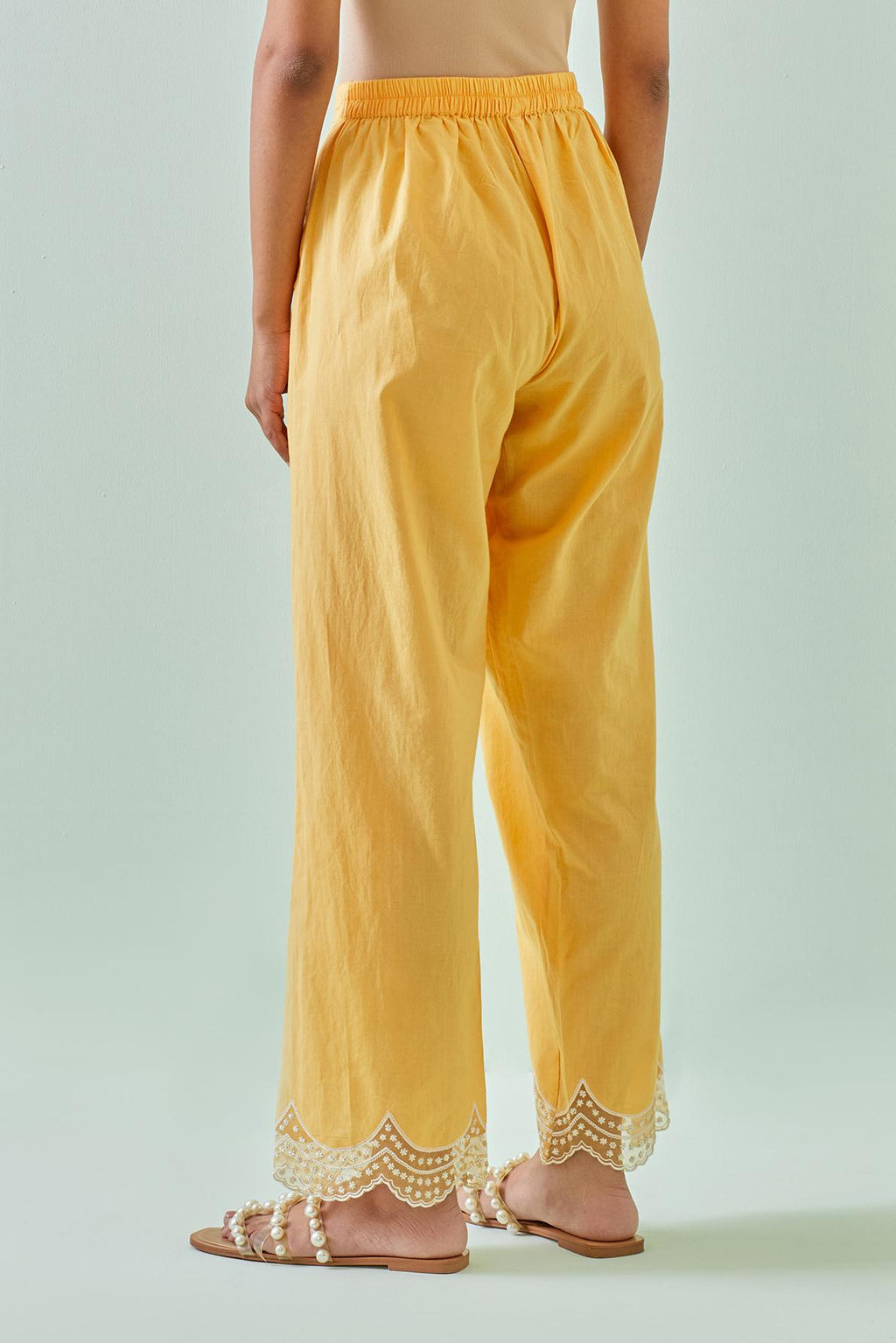 Yellow straight pants with scalloped embroidery at bottom hem.