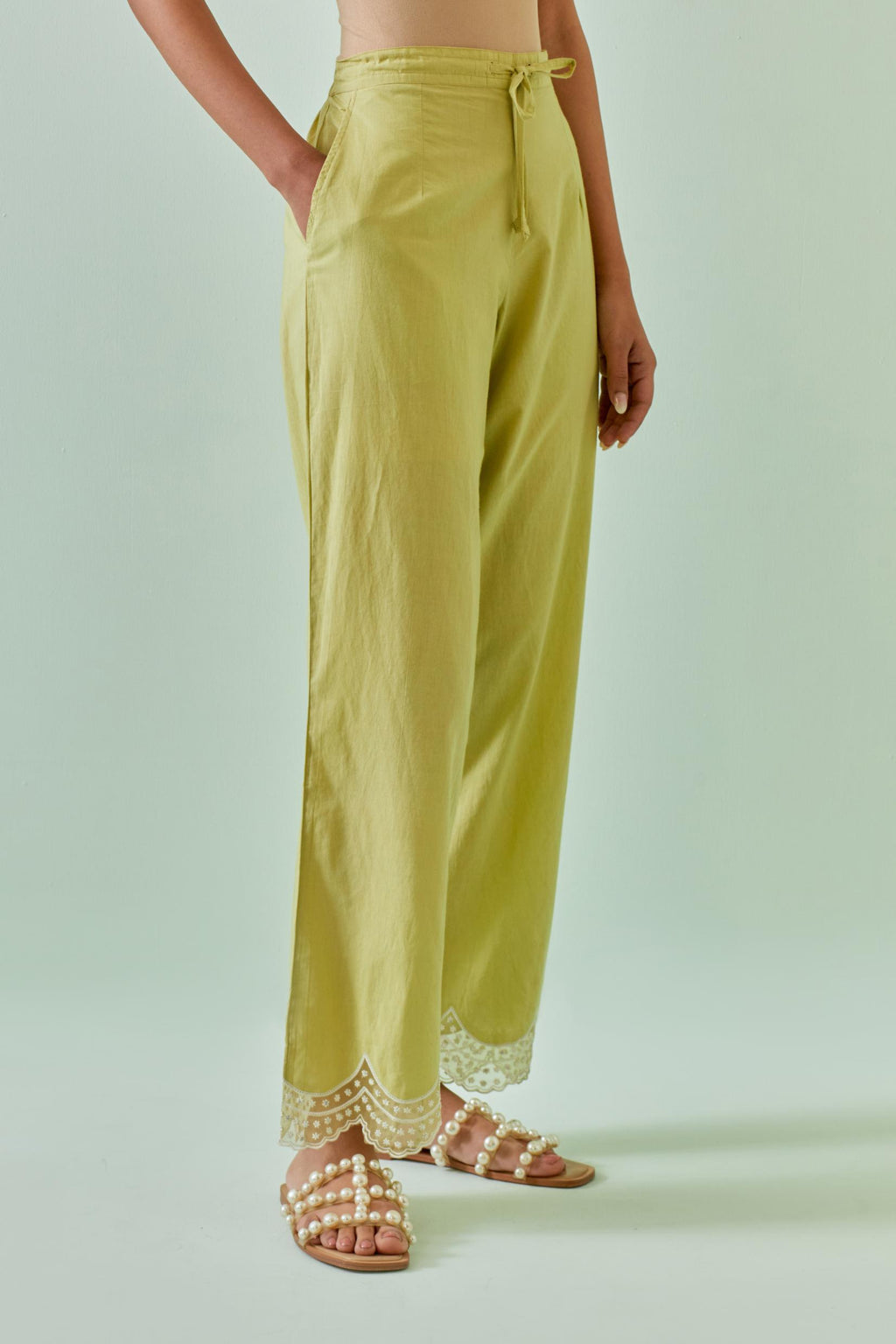 Green straight pants with scalloped embroidery at bottom hem.