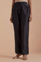 Dark grey silk chanderi straight pants detailed with scalloped organza edging at the hem, delicately highlighted with gold zari quilting.