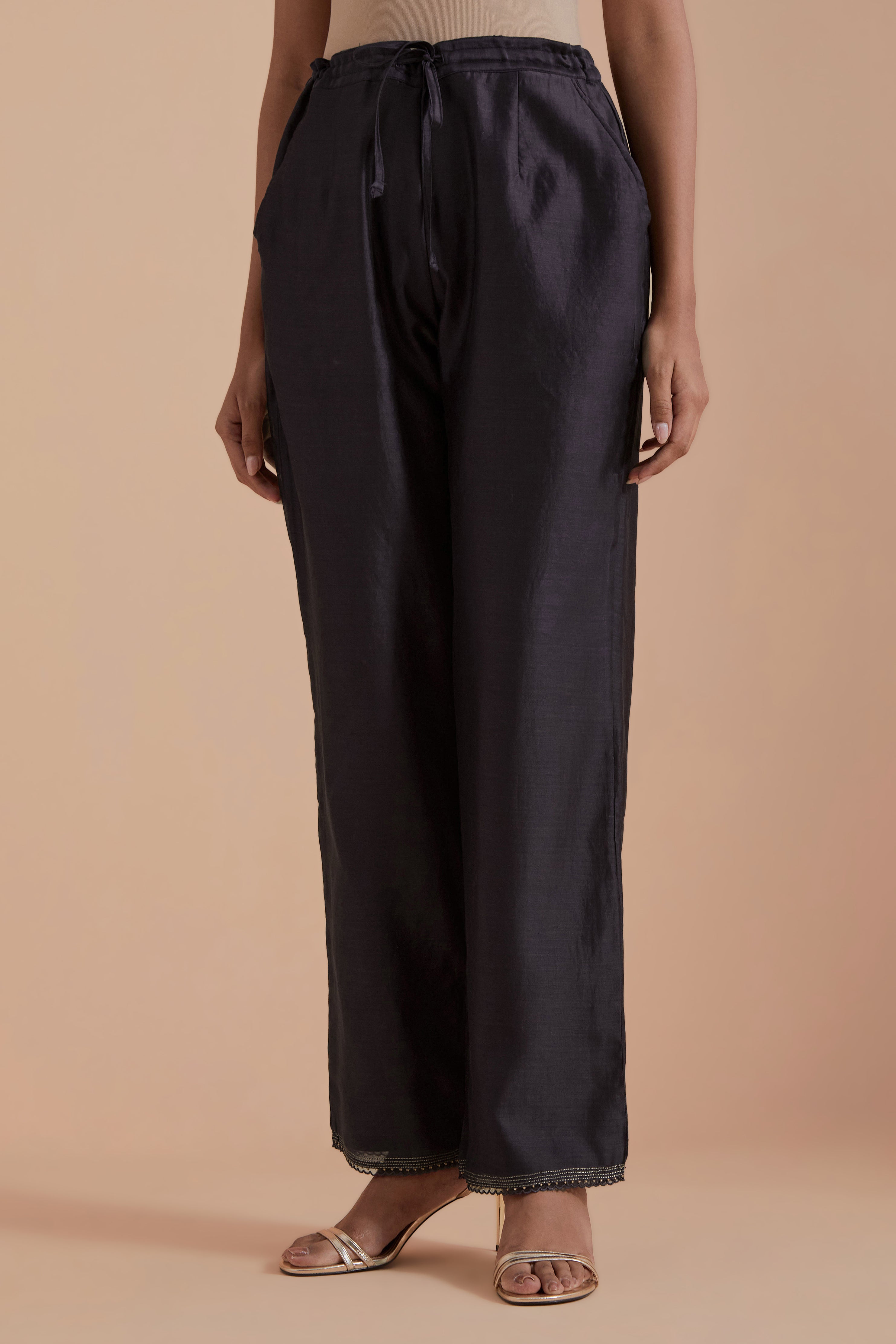 Dark grey silk chanderi straight pants detailed with scalloped organza edging at the hem, delicately highlighted with gold zari quilting.