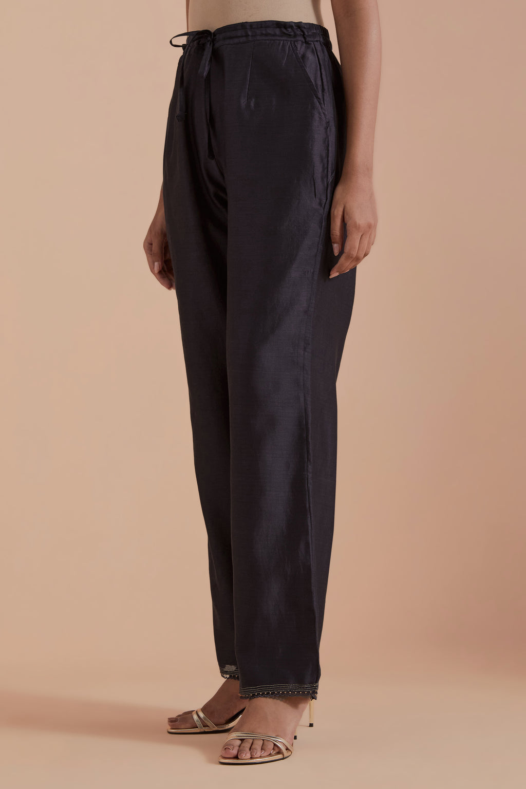 Dark grey silk chanderi straight pants detailed with scalloped organza edging at the hem, delicately highlighted with gold zari quilting.