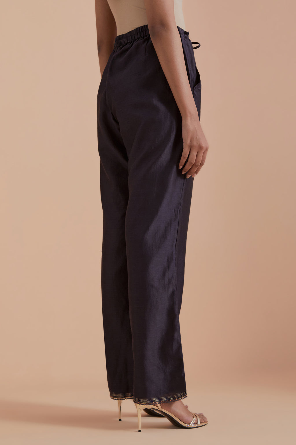 Dark grey silk chanderi straight pants detailed with scalloped organza edging at the hem, delicately highlighted with gold zari quilting.