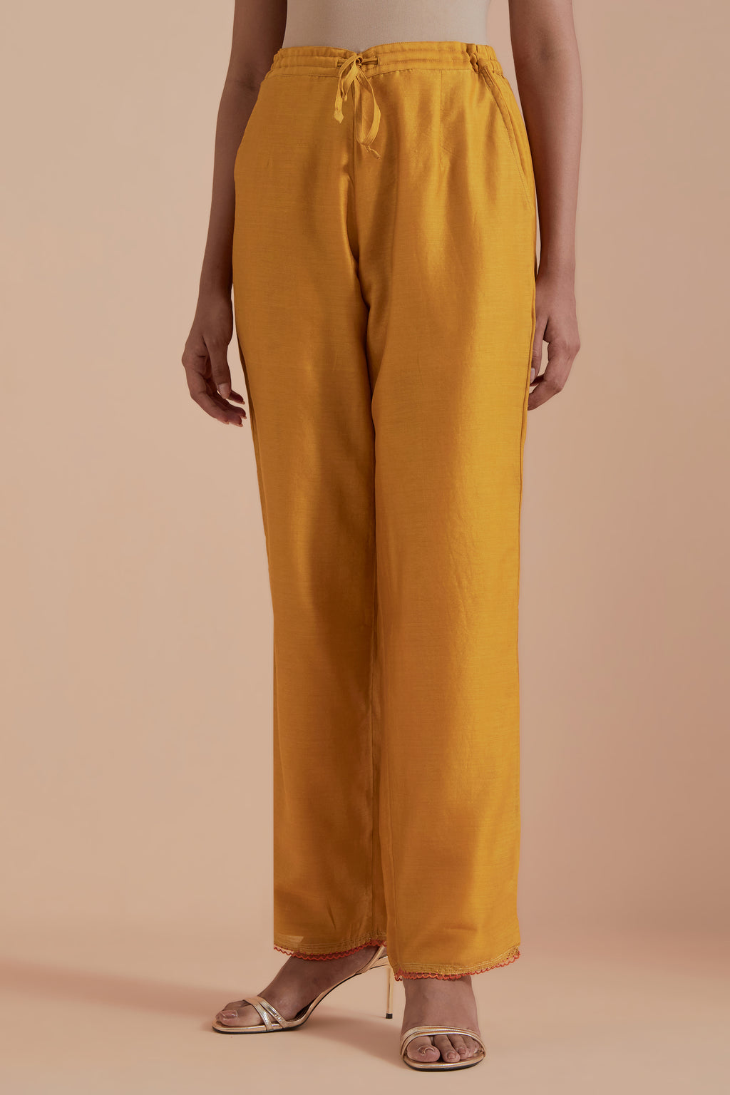 Mustard silk chanderi straight pants detailed with scalloped organza edging at the hem, delicately highlighted with gold zari quilting.