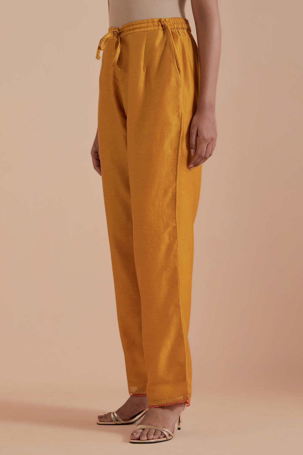 Mustard silk chanderi straight pants detailed with scalloped organza edging at the hem, delicately highlighted with gold zari quilting.