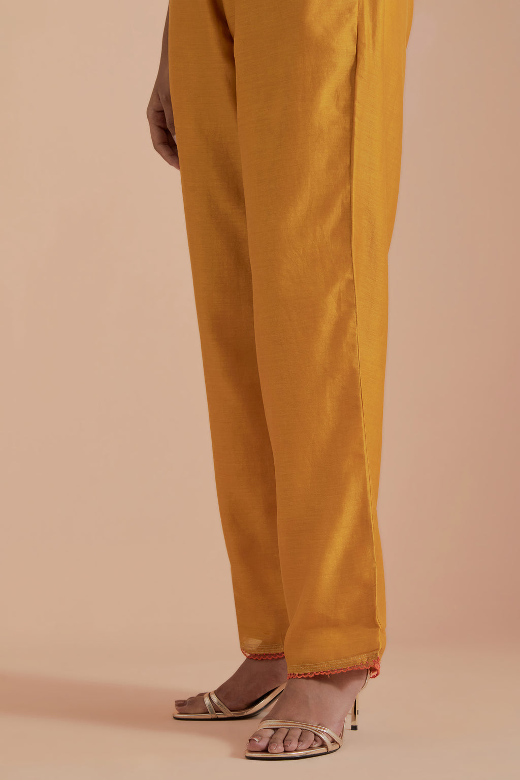 Mustard silk chanderi straight pants detailed with scalloped organza edging at the hem, delicately highlighted with gold zari quilting.