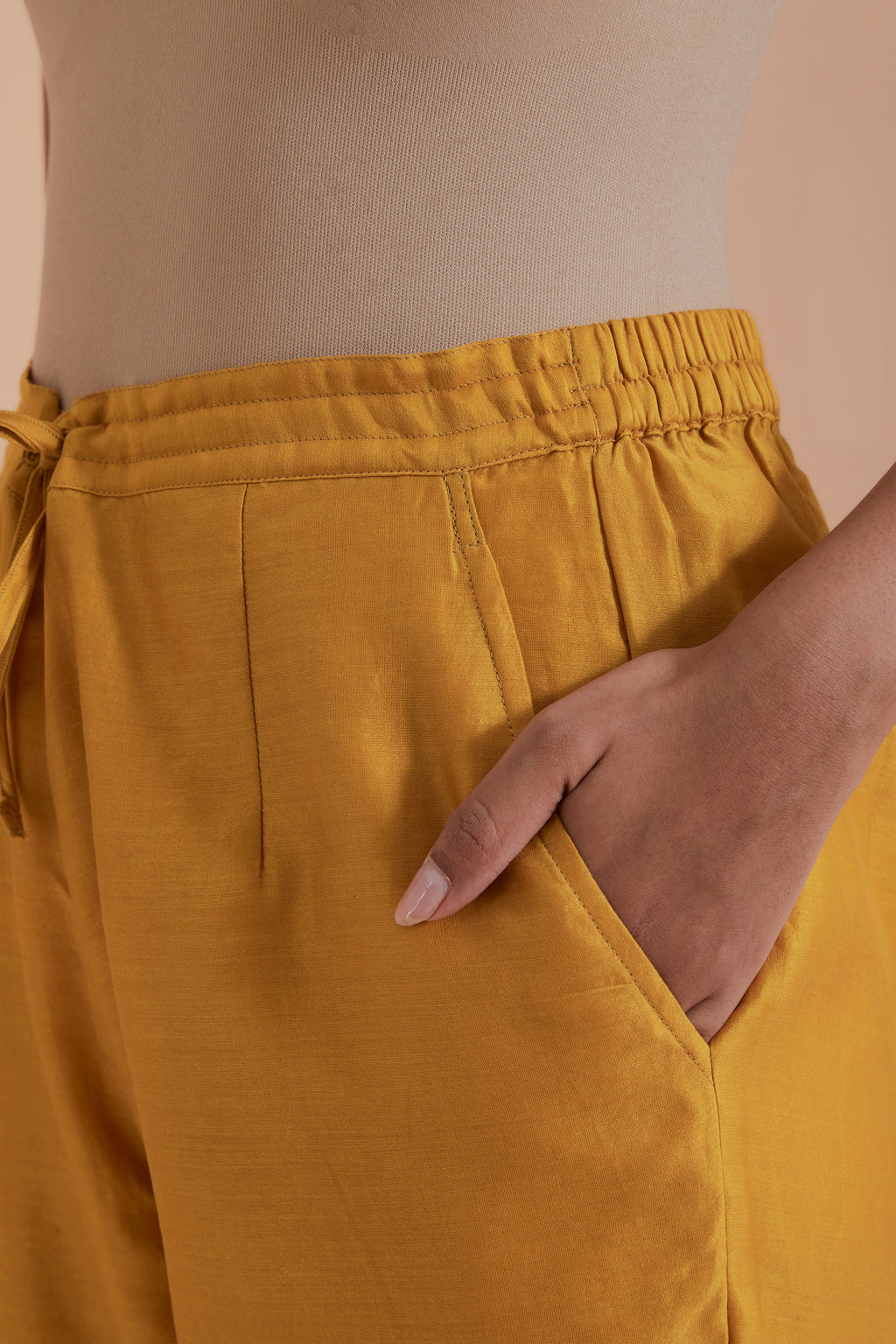 Mustard silk chanderi straight pants detailed with scalloped organza edging at the hem, delicately highlighted with gold zari quilting.