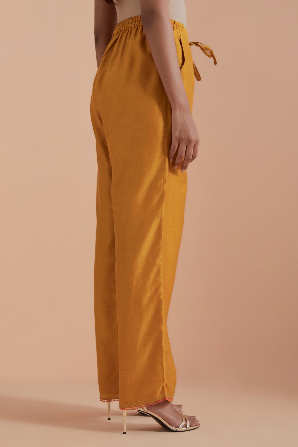 Mustard silk chanderi straight pants detailed with scalloped organza edging at the hem, delicately highlighted with gold zari quilting.