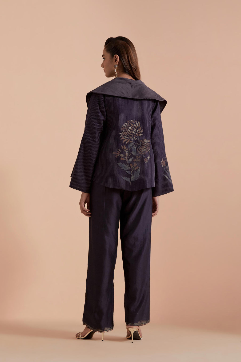 A Dark grey silk Chanderi jacket layered with quilted Silk Organza and delicate Silk Brocade floral appliquéd bootas. Paired with Dark grey silk chanderi straight pants.