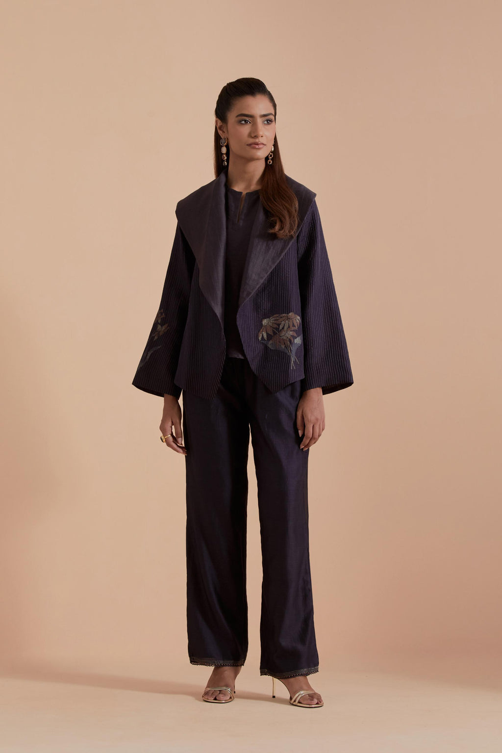 A Dark grey silk Chanderi jacket layered with quilted Silk Organza and delicate Silk Brocade floral appliquéd bootas. Paired with Dark grey silk chanderi straight pants.