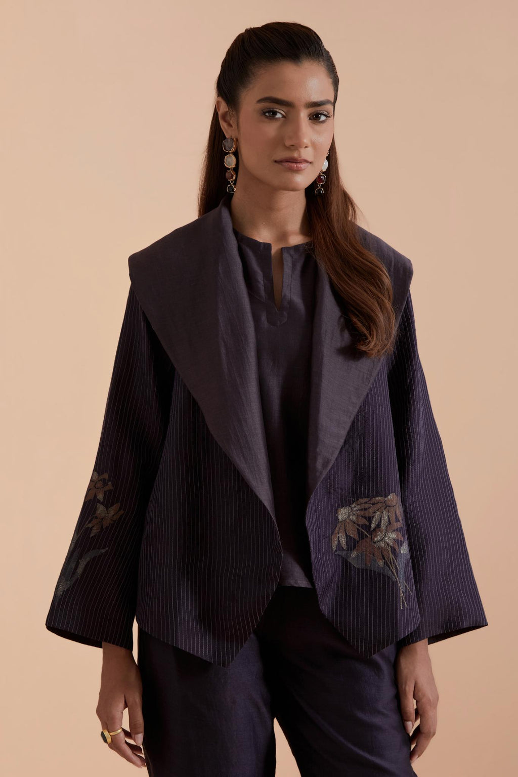 A Dark grey silk Chanderi jacket layered with quilted Silk Organza and delicate Silk Brocade floral appliquéd bootas. Paired with Dark grey silk chanderi straight pants.