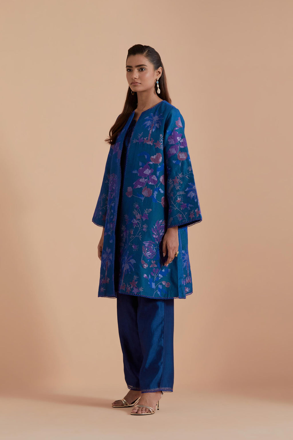 Blue short front open A-line jacket set layered with quilted Silk Organza and delicate Silk Brocade floral appliquéd bootas. Paired with Blue silk chanderi straight pants