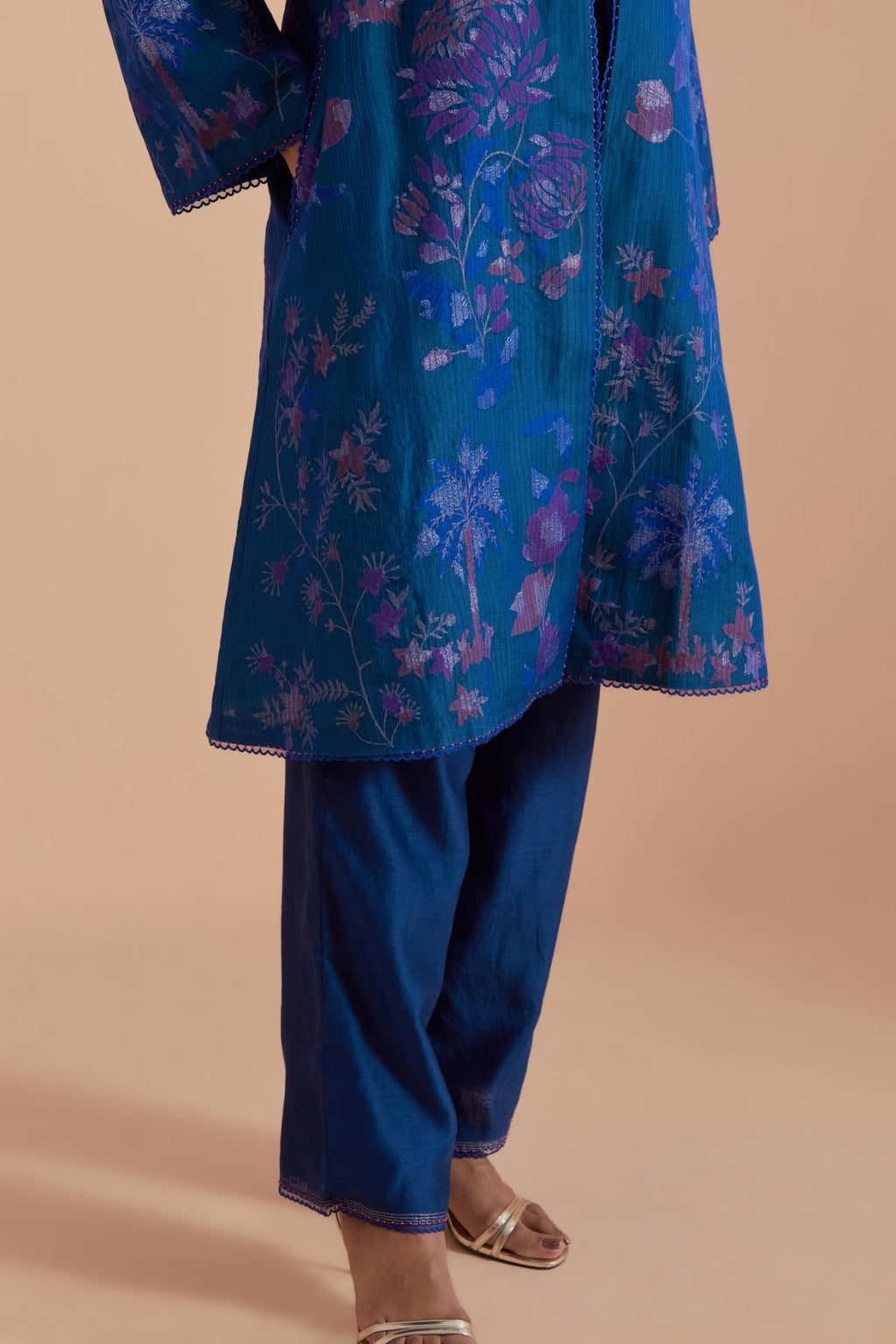 Blue short front open A-line jacket set layered with quilted Silk Organza and delicate Silk Brocade floral appliquéd bootas. Paired with Blue silk chanderi straight pants