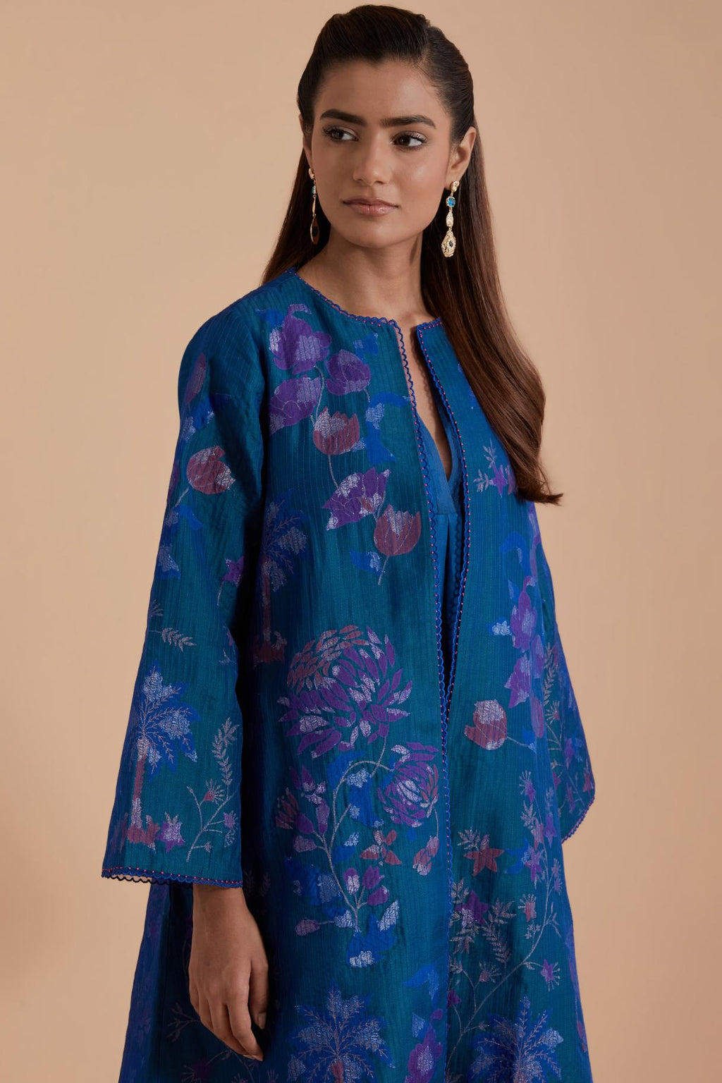 Blue short front open A-line jacket set layered with quilted Silk Organza and delicate Silk Brocade floral appliquéd bootas. Paired with Blue silk chanderi straight pants