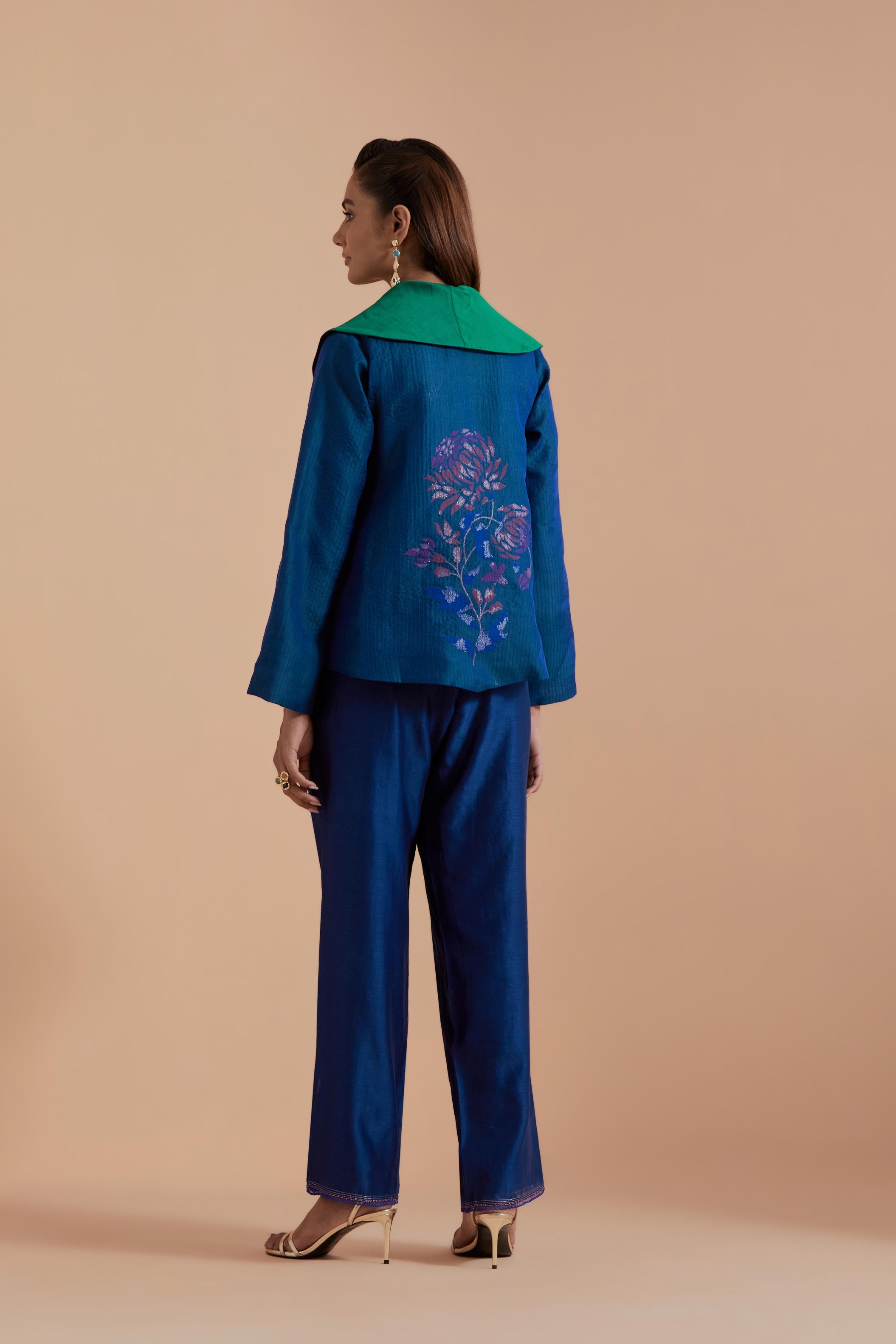 A Blue silk Chanderi jacket layered with quilted Silk Organza and delicate Silk Brocade floral appliquéd bootas. Paired with Blue silk chanderi straight pants.