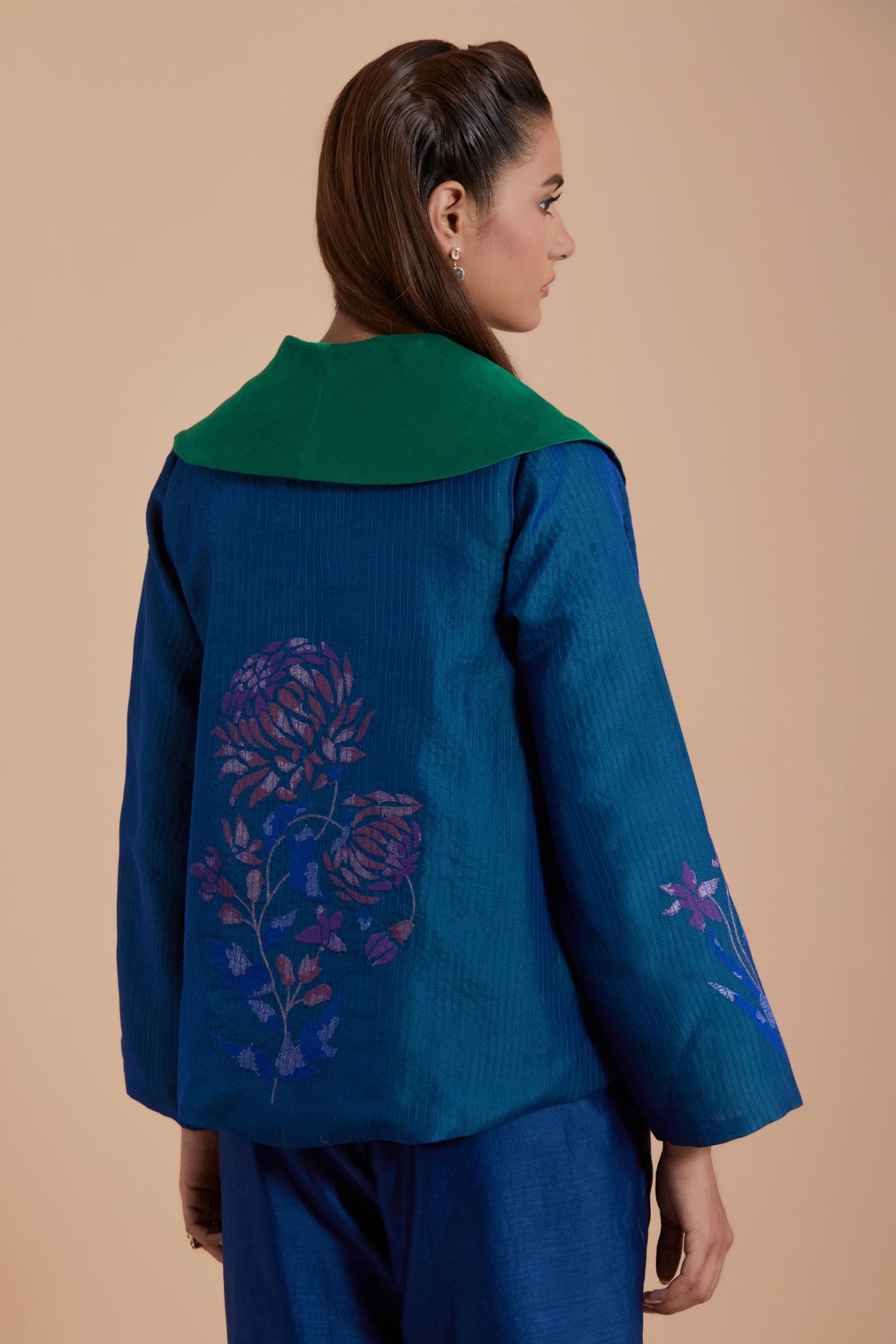 A Blue silk Chanderi jacket layered with quilted Silk Organza and delicate Silk Brocade floral appliquéd bootas. Paired with Blue silk chanderi straight pants.