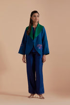 A Blue silk Chanderi jacket layered with quilted Silk Organza and delicate Silk Brocade floral appliquéd bootas. Paired with Blue silk chanderi straight pants.
