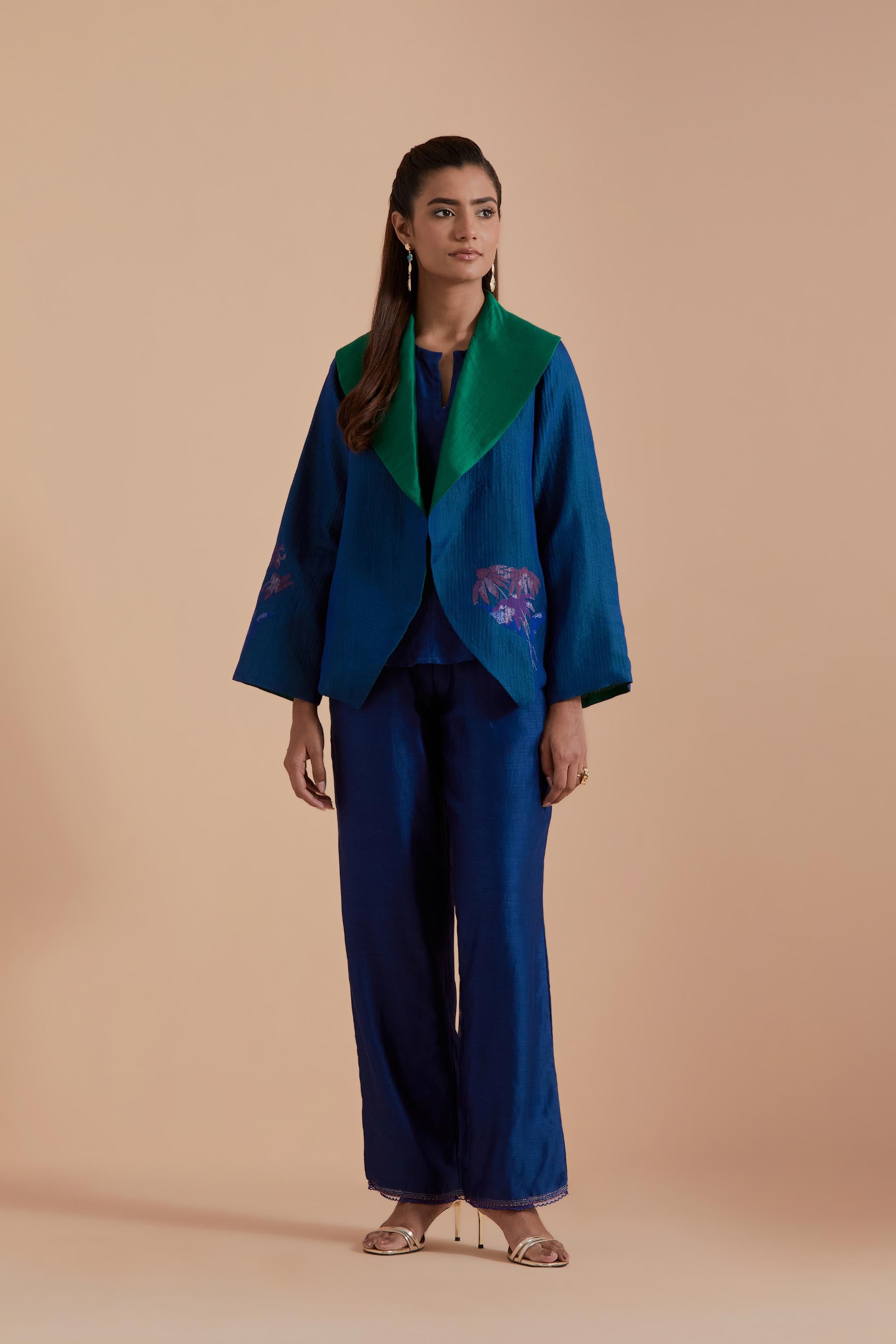 A Blue silk Chanderi jacket layered with quilted Silk Organza and delicate Silk Brocade floral appliquéd bootas. Paired with Blue silk chanderi straight pants.