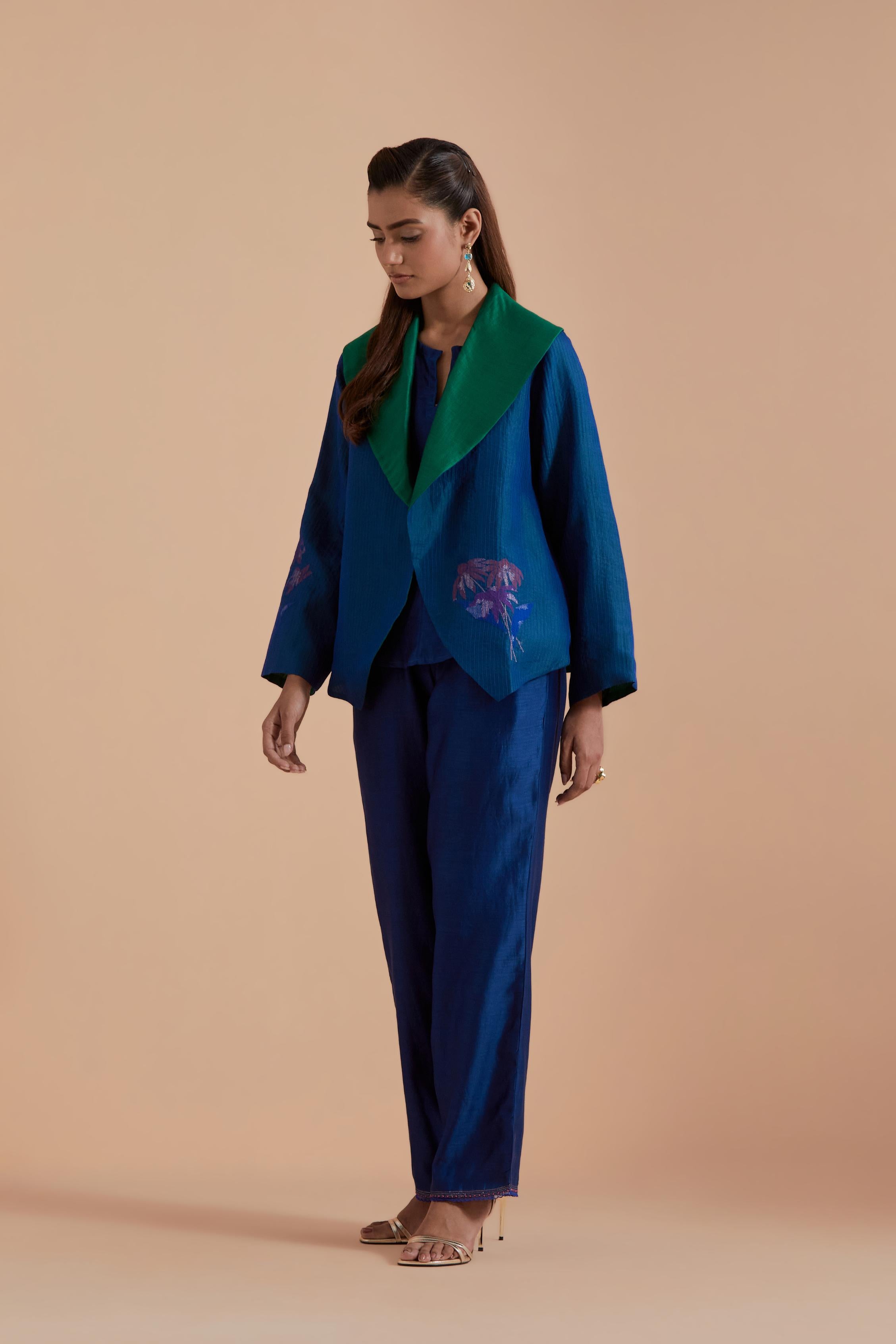 A Blue silk Chanderi jacket layered with quilted Silk Organza and delicate Silk Brocade floral appliquéd bootas. Paired with Blue silk chanderi straight pants.