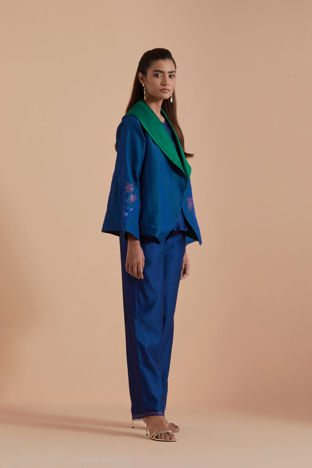 A Blue silk Chanderi jacket layered with quilted Silk Organza and delicate Silk Brocade floral appliquéd bootas. Paired with Blue silk chanderi straight pants.