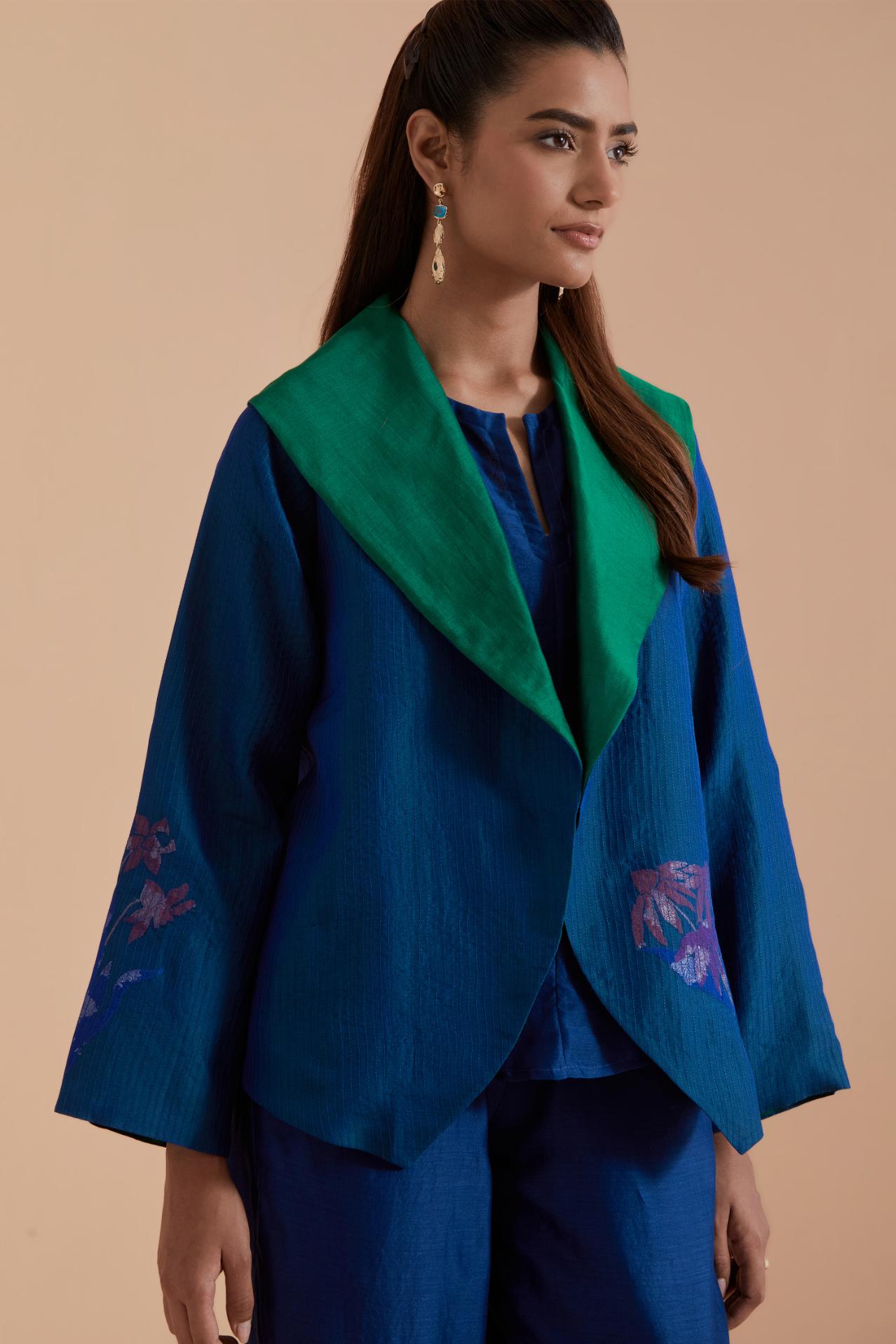 A Blue silk Chanderi jacket layered with quilted Silk Organza and delicate Silk Brocade floral appliquéd bootas. Paired with Blue silk chanderi straight pants.