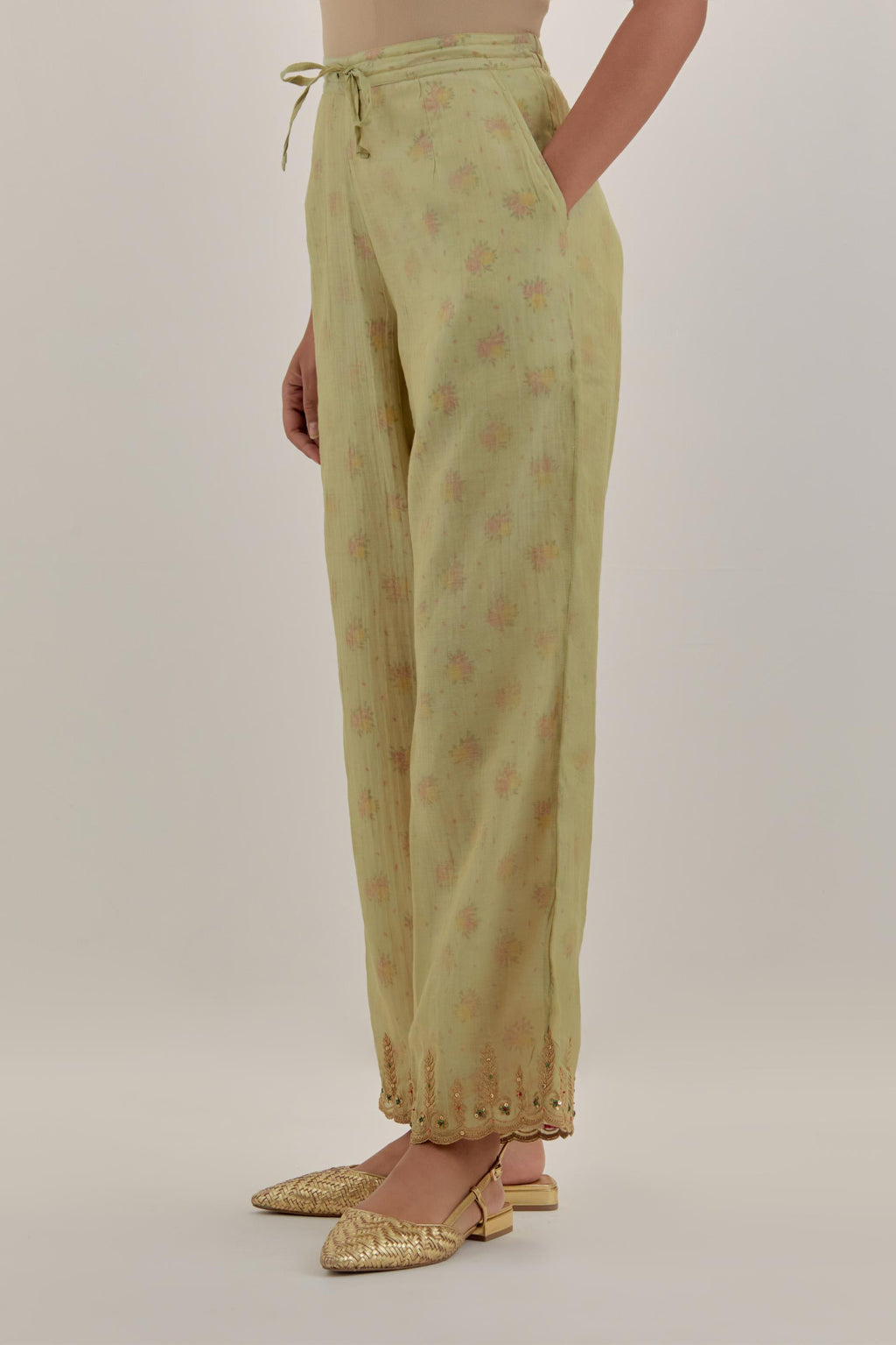 Green tissue chanderi straight pants with light gold dori embroidery at hem.