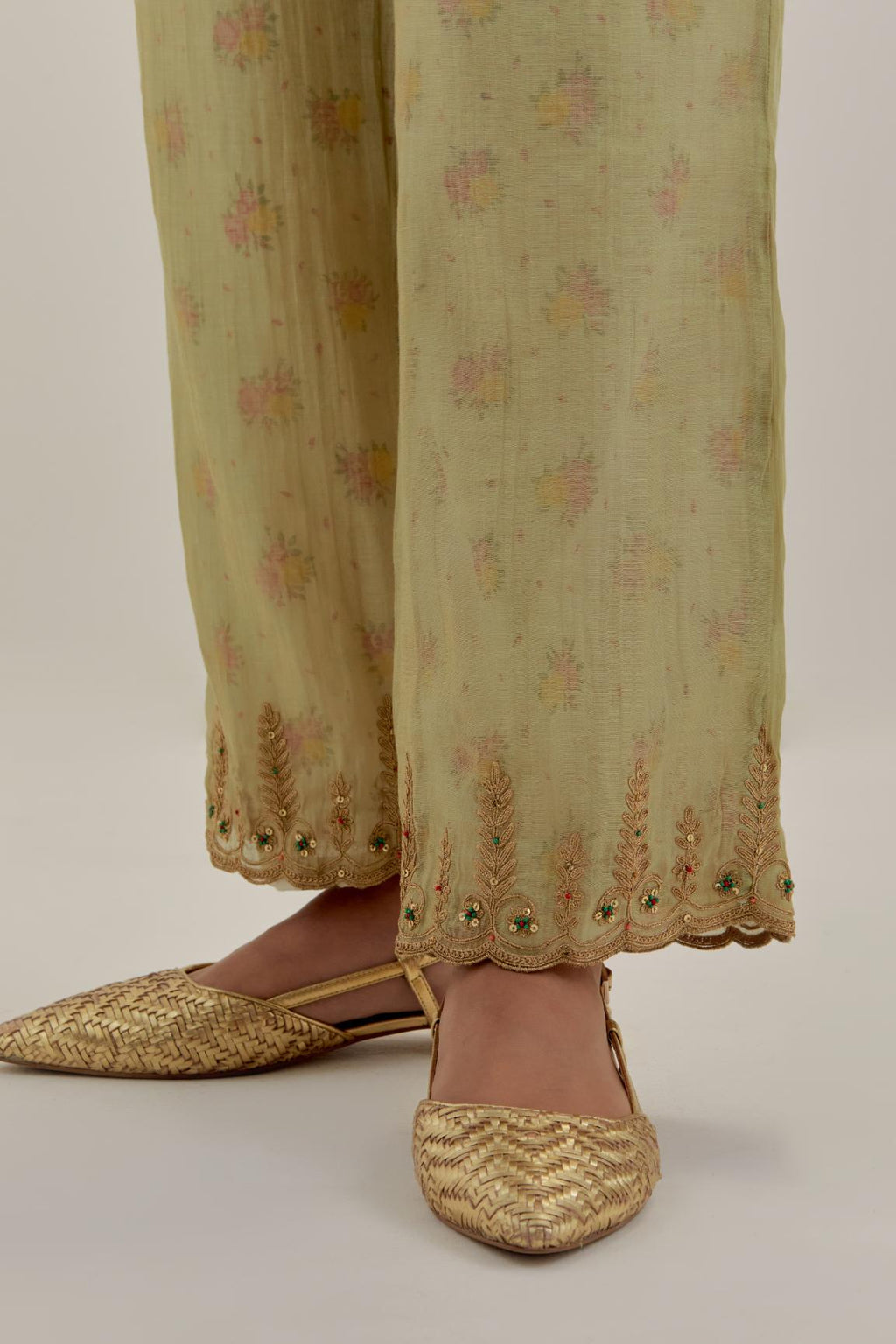 Green tissue chanderi straight pants with light gold dori embroidery at hem.