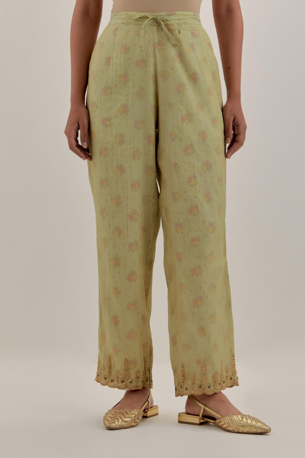 Green tissue chanderi straight pants with light gold dori embroidery at hem.