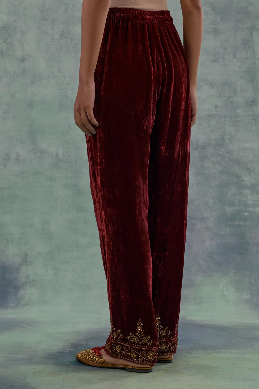 Deep maroon velvet straight pants. The hem is highlighted with hand-embroidered bead, sequins and zari motifs.