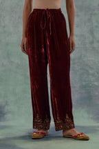 Deep maroon velvet straight pants. The hem is highlighted with hand-embroidered bead, sequins and zari motifs.