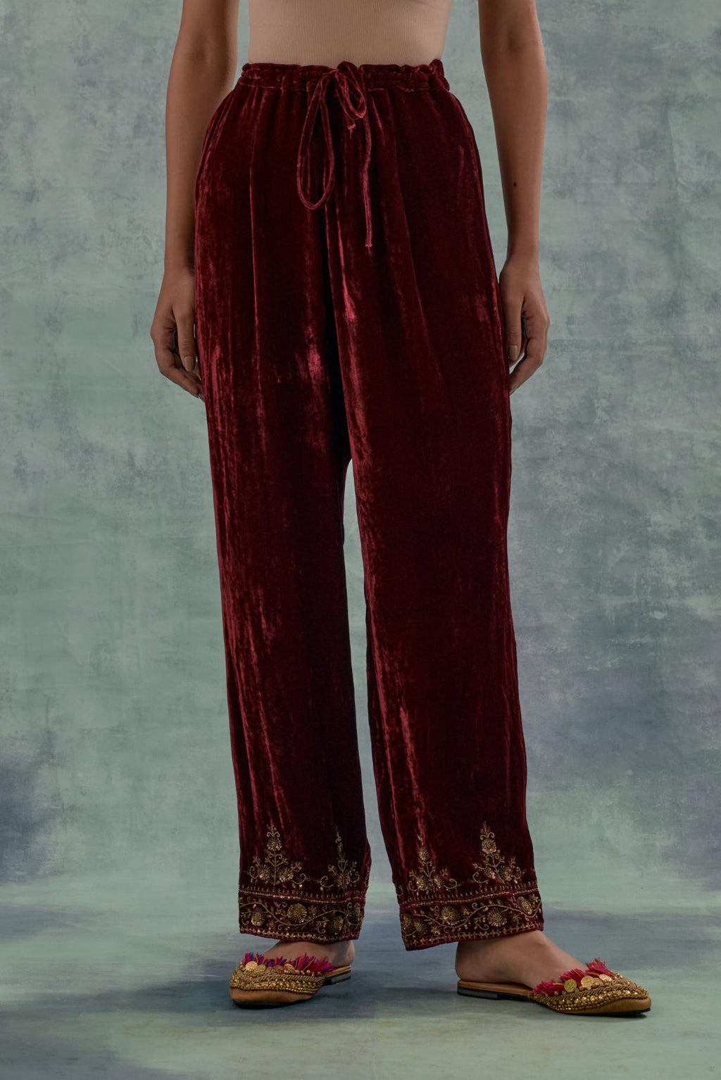 Deep maroon velvet straight pants. The hem is highlighted with hand-embroidered bead, sequins and zari motifs.